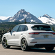 A white Porsche Cayenne SUV parked in front of a mountain.